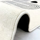 Close-up of a white rug with textured border on a light background
