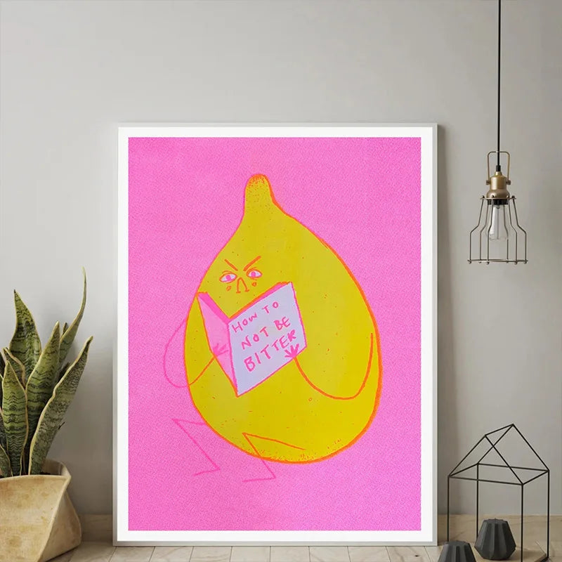 Framed artwork of a yellow lemon with a pink background and text, placed on a wall.