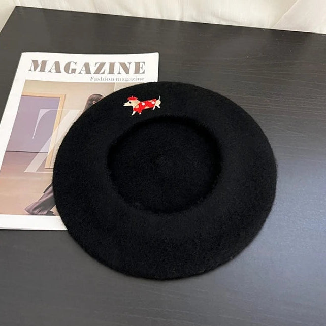 Black beret on a dark surface with a magazine underneath, featuring 'COISINI STUDIO' branding.