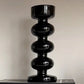 Black decorative vase with spiral design on a neutral background