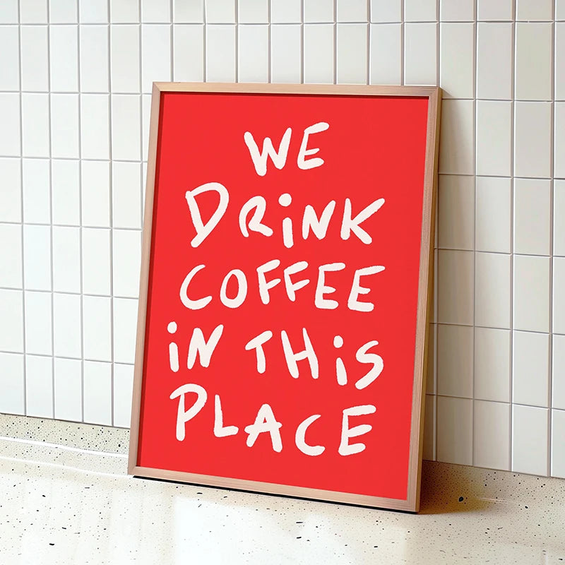 Red framed poster with 'We Drink Coffee In This Place' text on a tiled wall.
