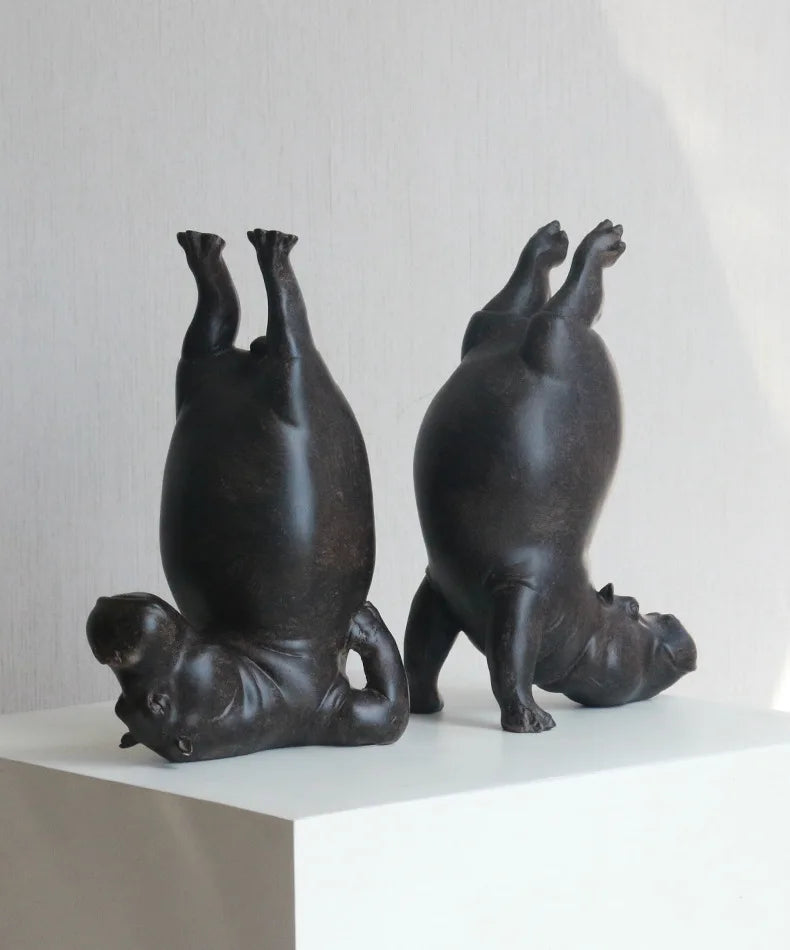 Two black ceramic pig sculptures on a white surface with a light gray background