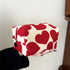 Red and white heart-patterned pouch held by a person against a neutral background