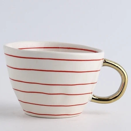 White mug with red stripes and a gold handle on a light gray background