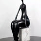 Black abstract sculpture on a marble base against a white background