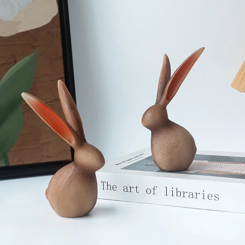Two wooden rabbit figurines on a book with a blurred background