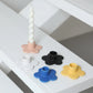 Set of colorful flower-shaped candle holders on a white surface.