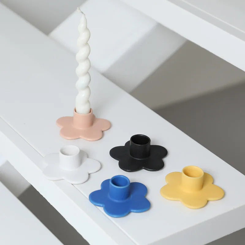Set of colorful flower-shaped candle holders on a white surface.