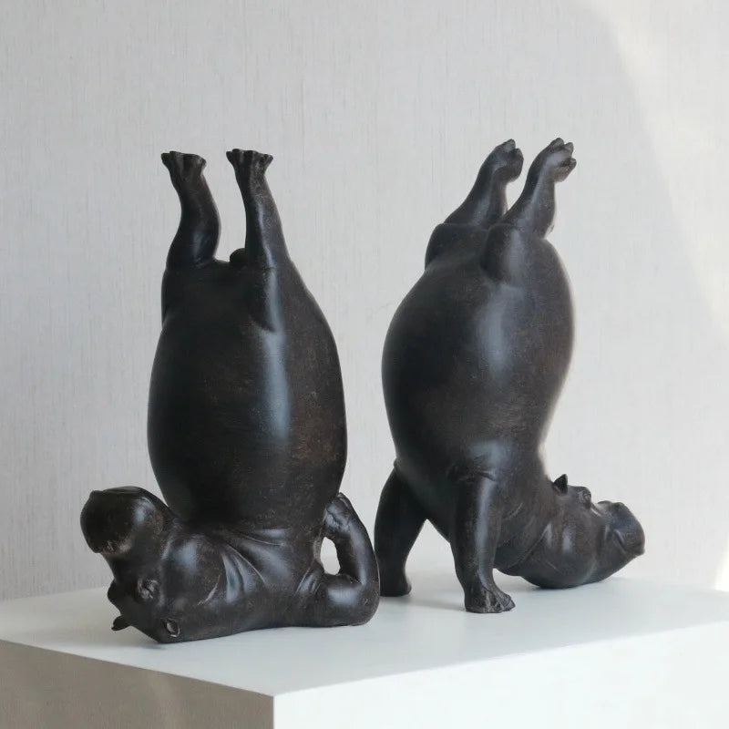 Two black ceramic sculptures of dogs standing on their hind legs on a white surface with a light gray background.