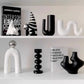 White and black decorative vases on a shelf against a white background