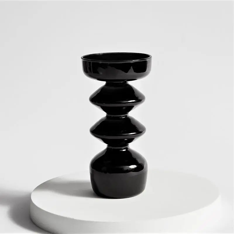 Black ceramic candle holder on a white pedestal against a light gray background