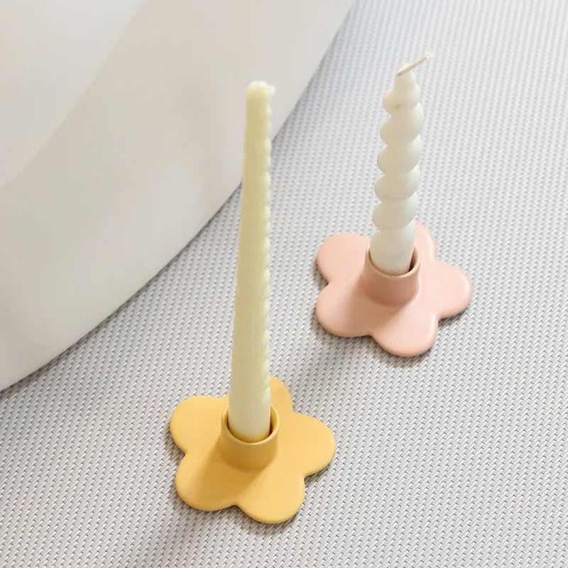 Two candle holders with candles on a textured surface