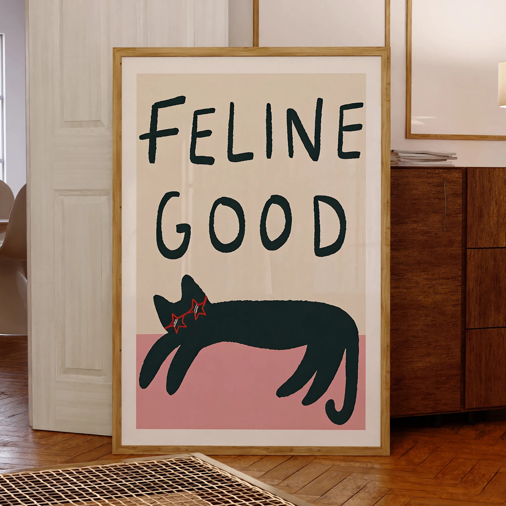 Framed artwork with 'Feline Good' text and a black cat illustration on a beige background.