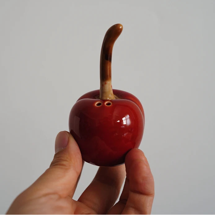 Hand holding a red ceramic fish with a white background
