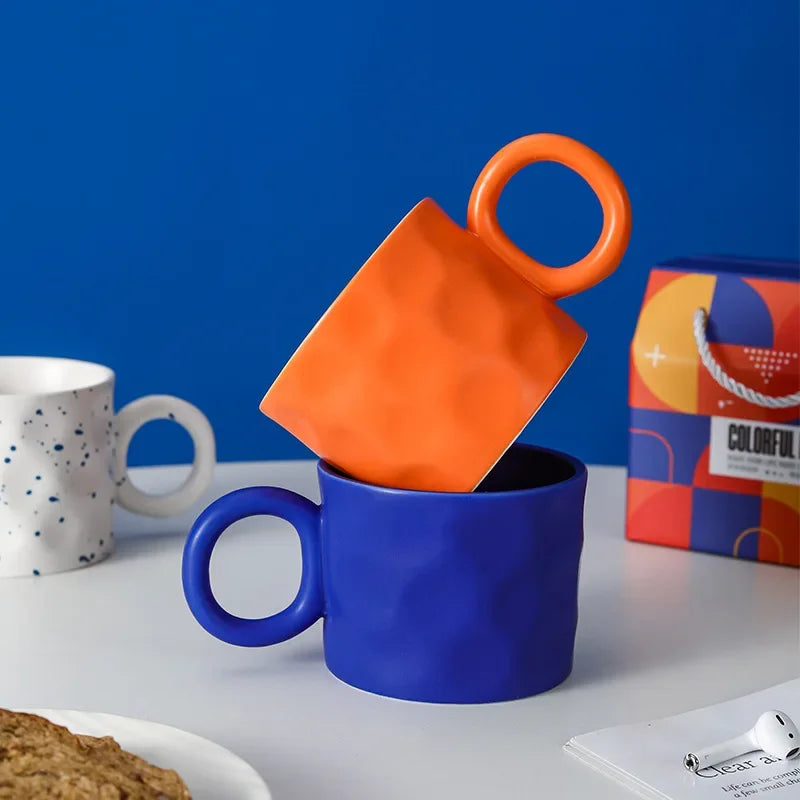Blue mug with an orange square and handle on a white surface against a blue background