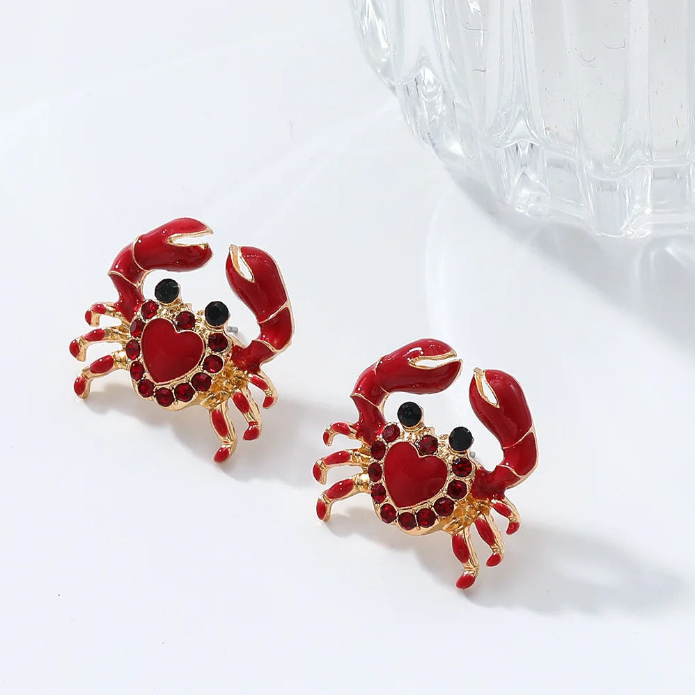 Red crab-shaped earrings with gold accents on a white background