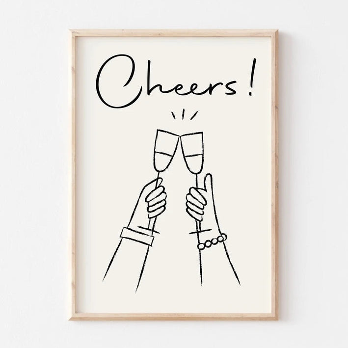 Framed artwork with 'Cheers!' text and line drawings of clinking champagne glasses on a white background.