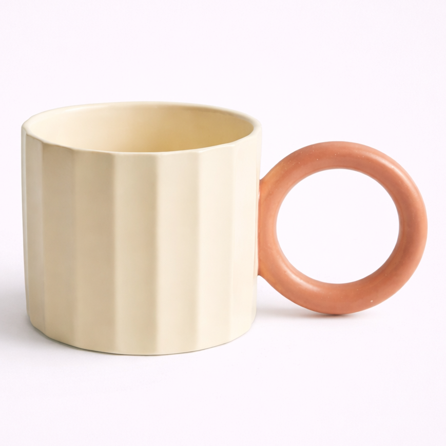 Beige ceramic mug with contrasting pink handle on white background
