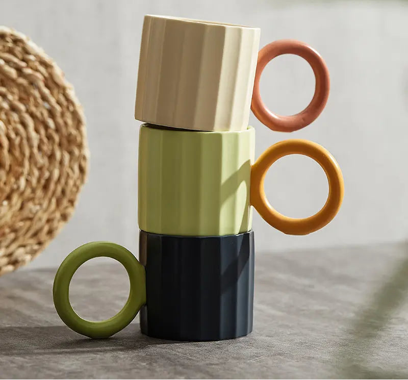 Stack of colorful ceramic mugs with ring handles