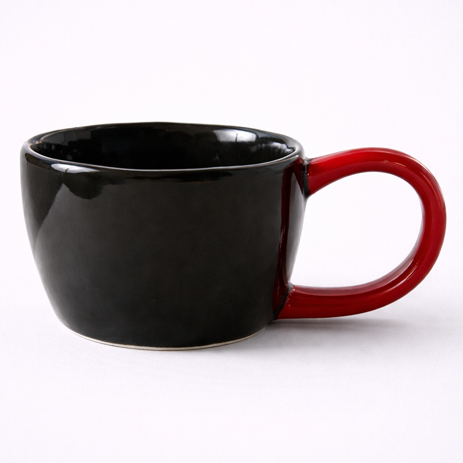Black mug with a red handle on a white background