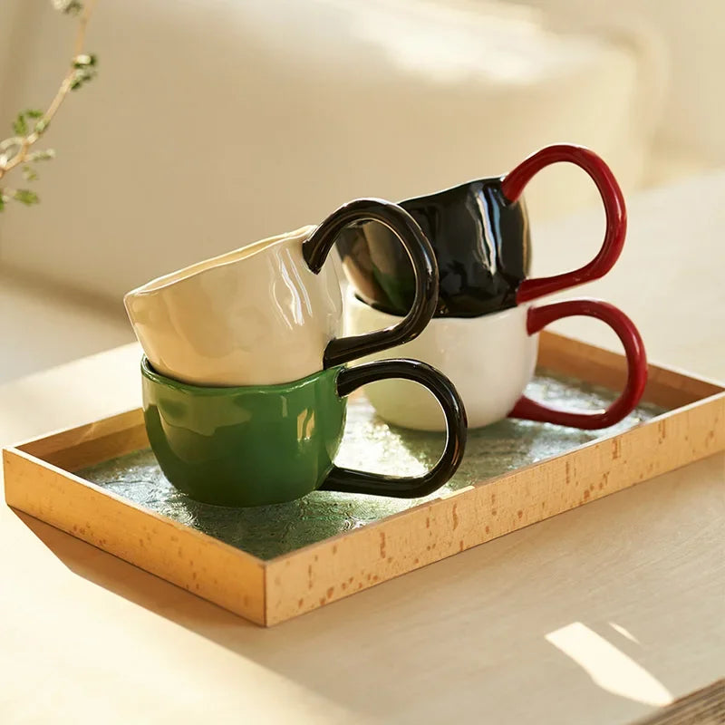 Set of four ceramic mugs in different colors on a wooden tray.