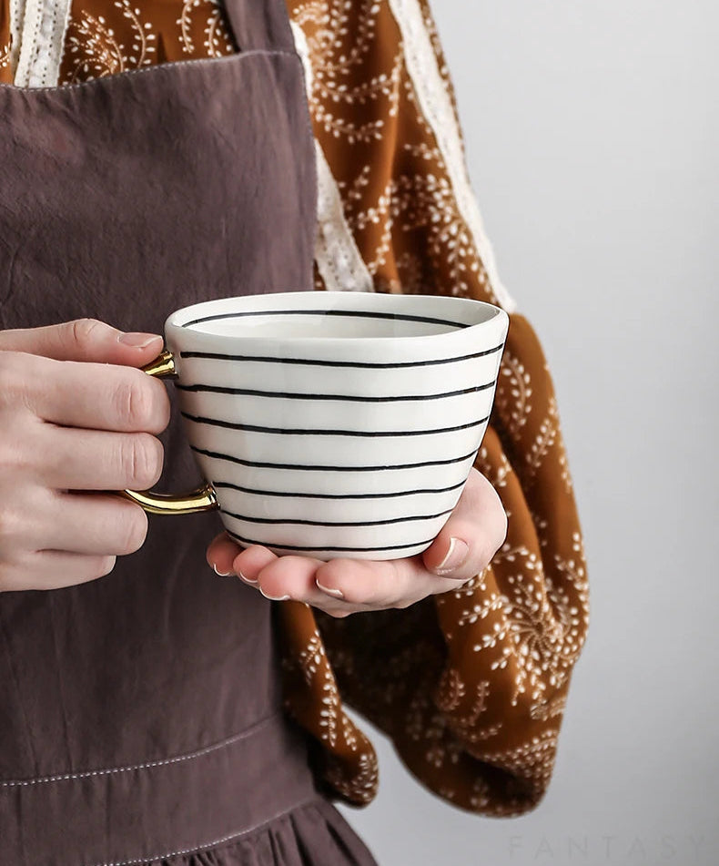 Person holding a striped ceramic mug with a neutral background