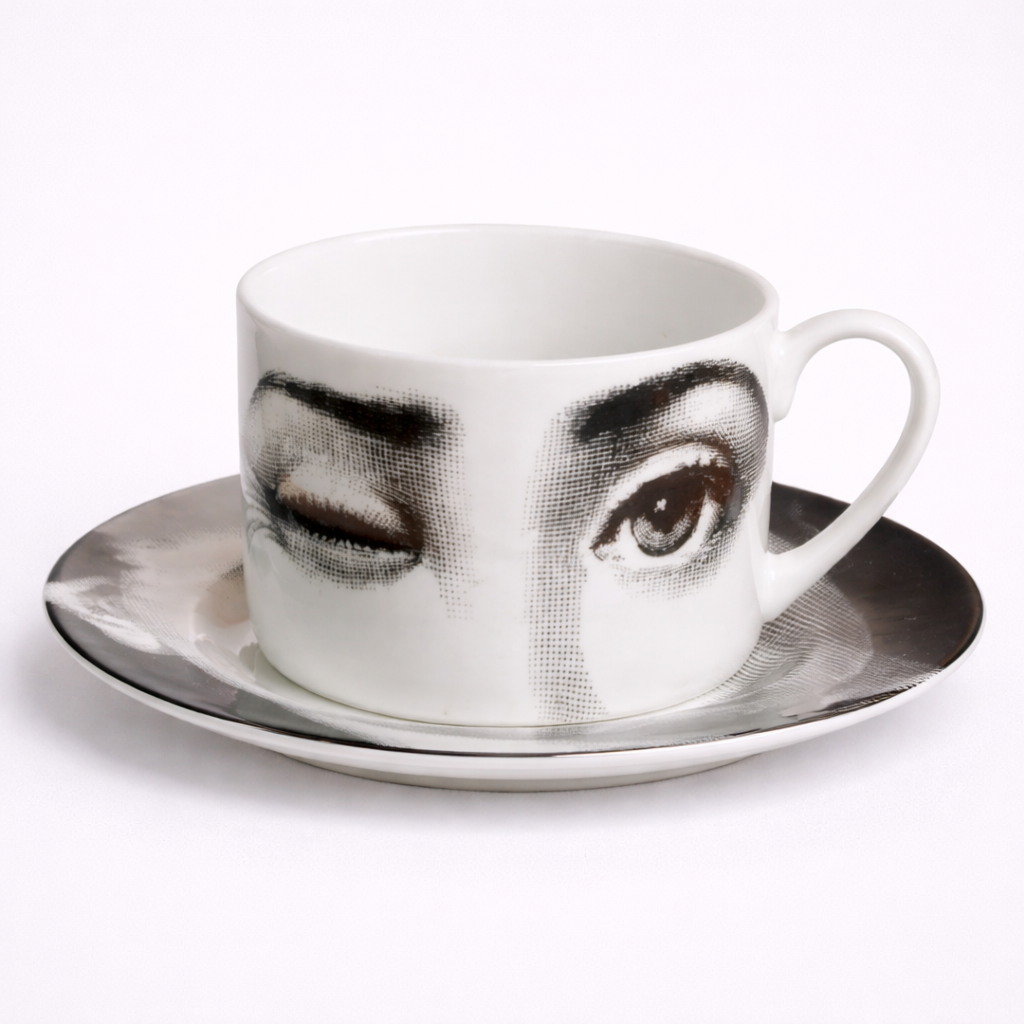 Ceramic cup and saucer with artistic face design on a white background