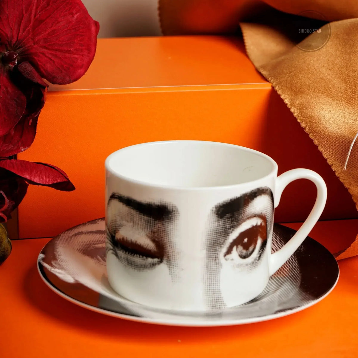 Ceramic cup with artistic design on a saucer against an orange background