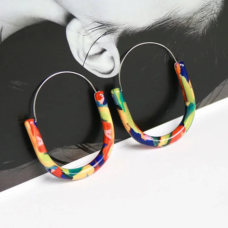 Colorful hoop earrings worn by a person with a black and white background