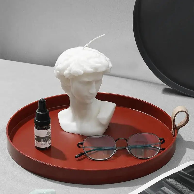 Red tray with a white bust sculpture, black dropper bottle, and sunglasses on a gray surface - alternate view 3