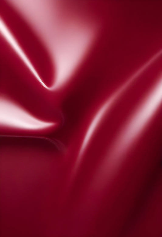 Close-up of smooth burgundy fabric exhibiting gentle folds and light reflections