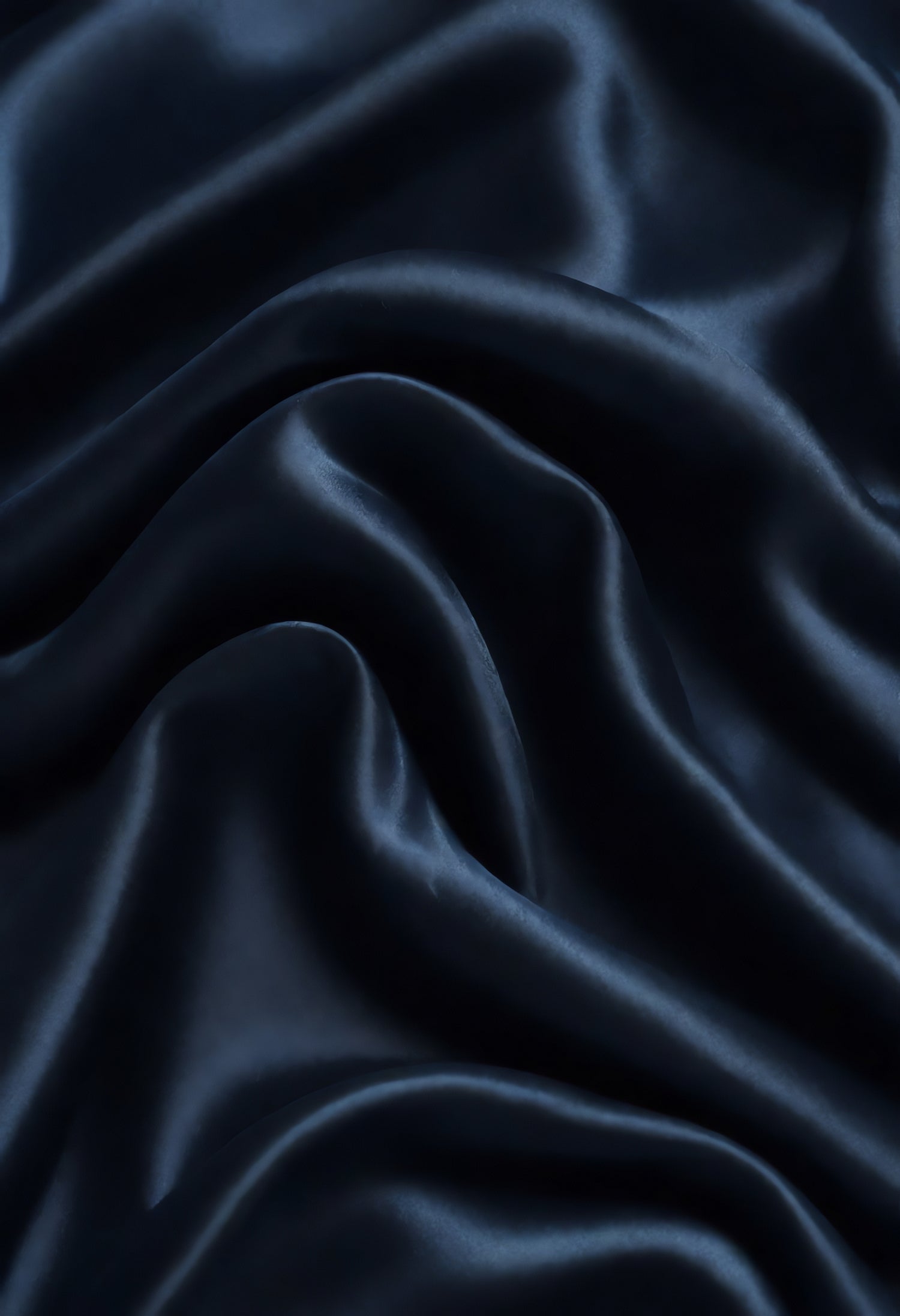 Rich navy blue fabric draped elegantly on a surface, showcasing smooth texture and gentle folds in warm lighting