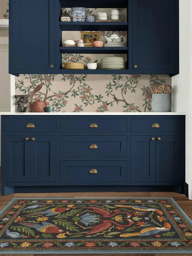 Navy blue kitchen cabinets with floral wallpaper and rug.