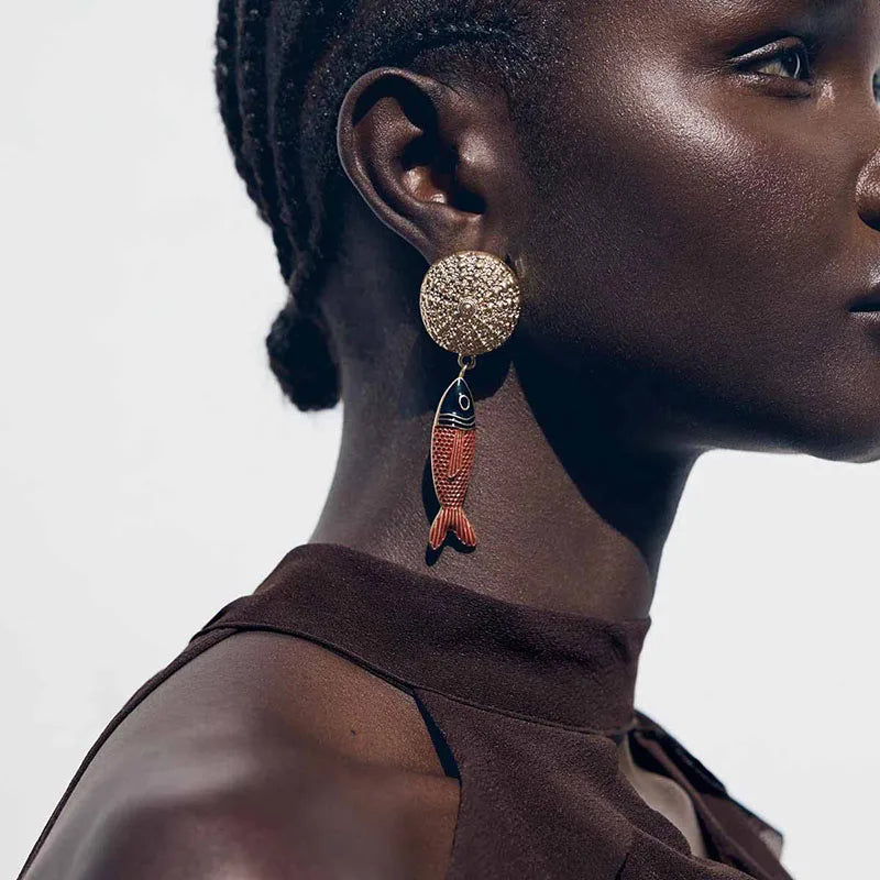 Close-up of a woman wearing a fish-shaped earring with a neutral background