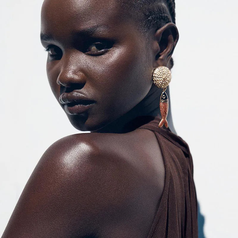Woman wearing a brown top and large earrings against a white background