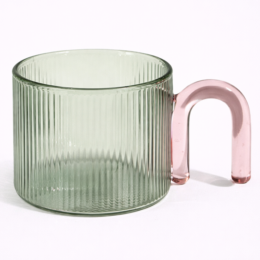 Green glass mug with a pink handle on a white background