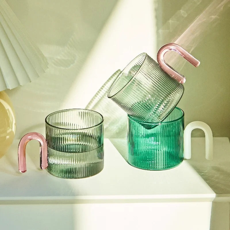 Green glass containers with pink handles on a white surface
