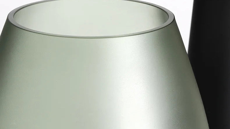 Green rounded glass vase holding white flowering branches