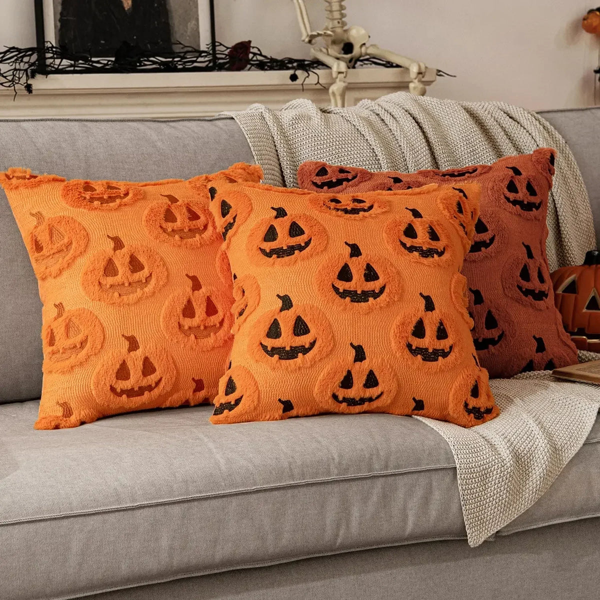Orange pillows with jack-o'-lantern patterns on a gray couch.