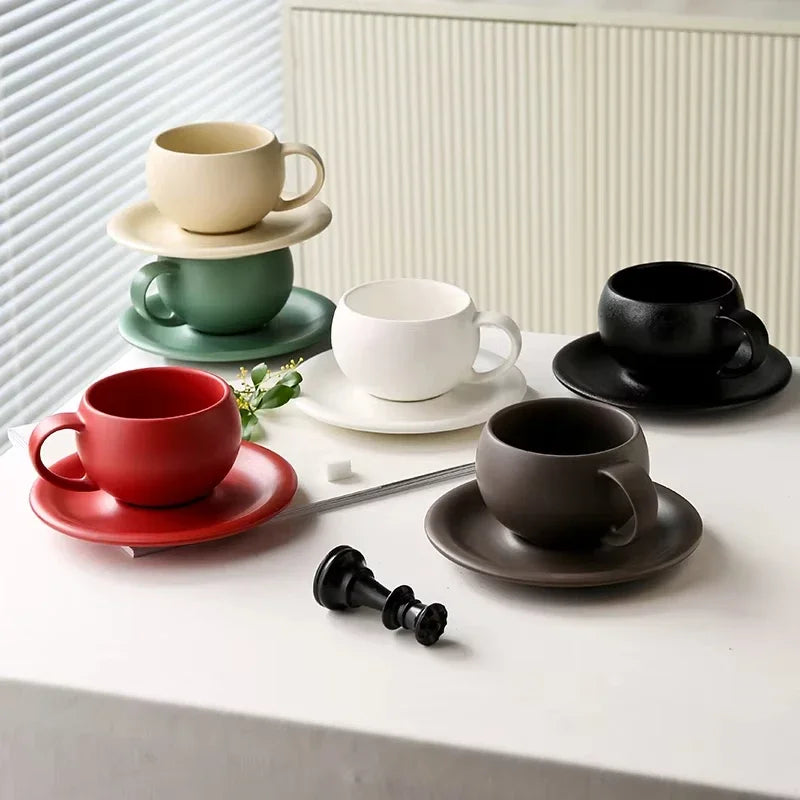 Set of colorful ceramic cups and saucers on a white surface with a neutral background.