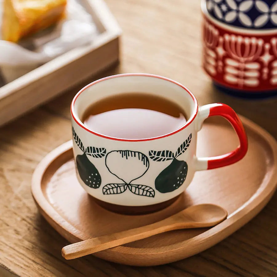 Ceramic mug with red handle on a wooden tray with a wooden spoon, on a wooden surface.