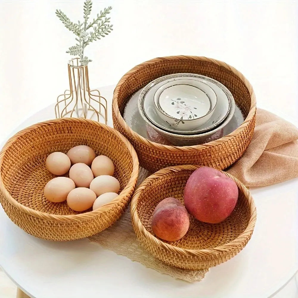Three woven baskets with eggs, peaches, and stacked bowls on a white surface.