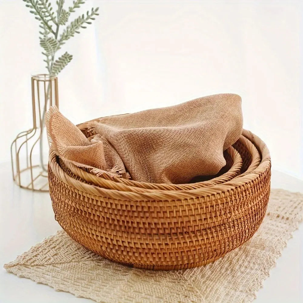 Woven basket with a beige towel on a light surface with a blurred plant in the background