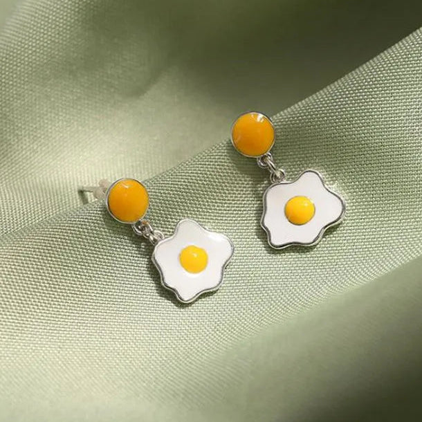 Egg-shaped earrings on a green fabric background