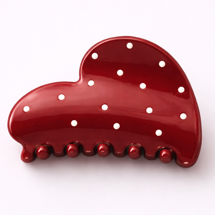 Red heart-shaped object with white polka dots on a white background