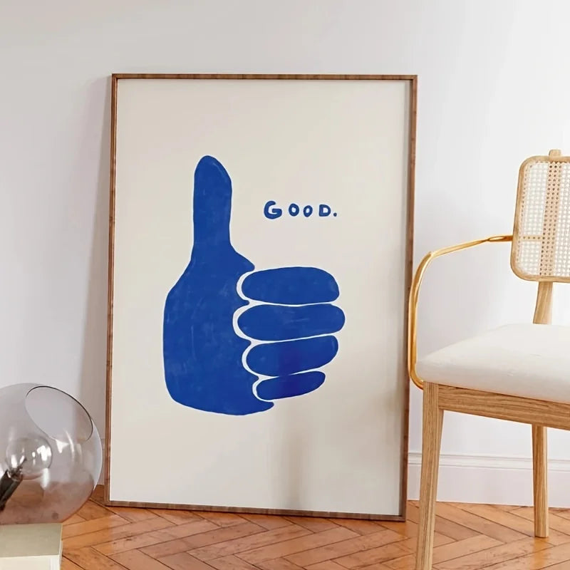 Framed artwork with a blue hand gesture and 'GOOD.' text on a white wall.