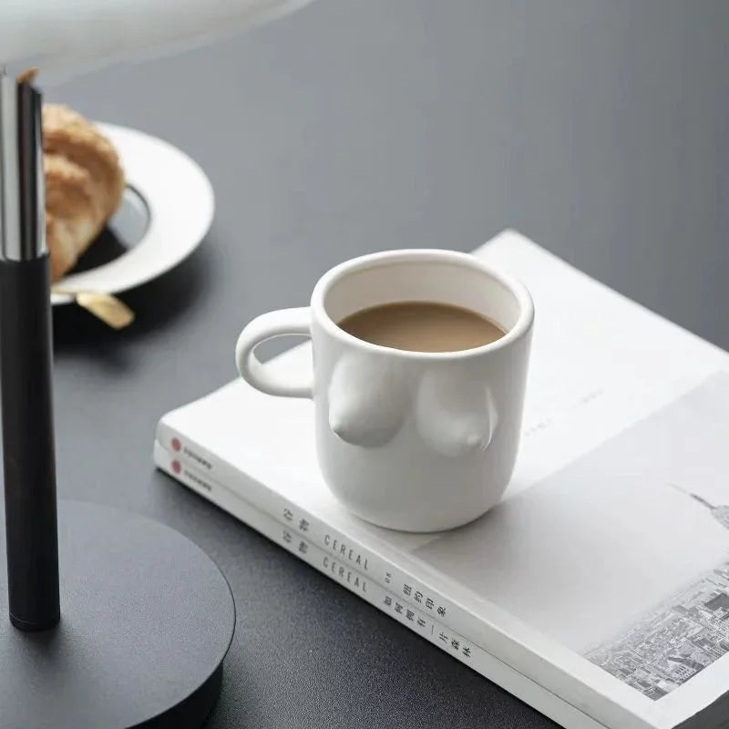 White mug with a unique design on a book, filled with coffee, on a gray surface.