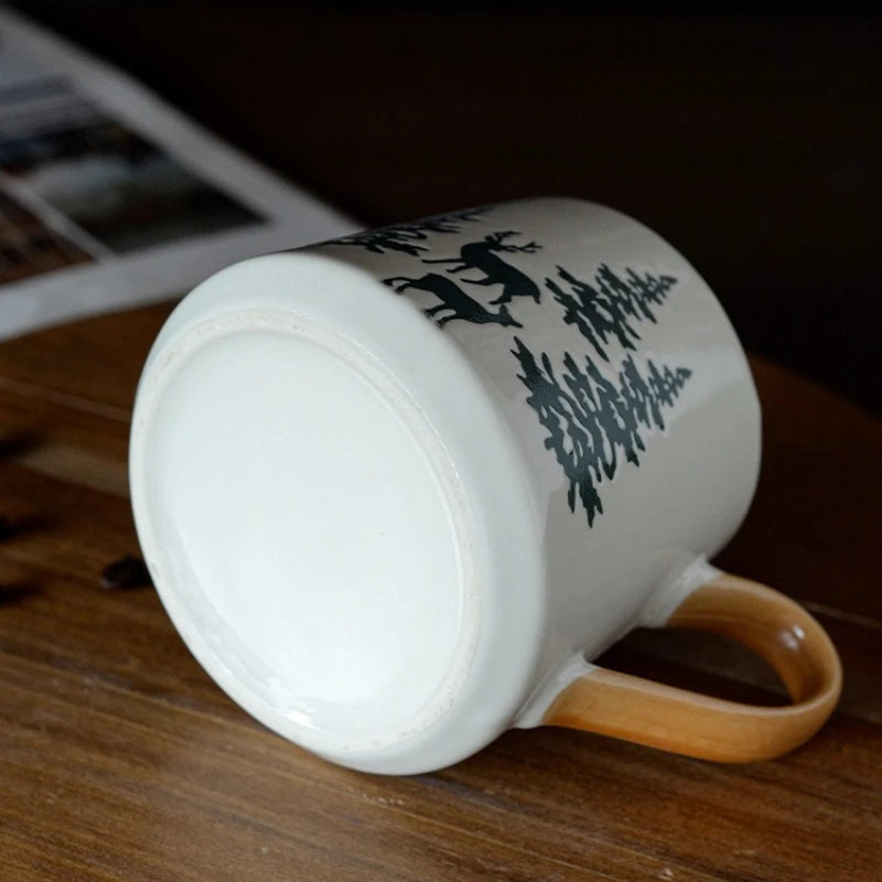 White mug with black tree design on a wooden surface