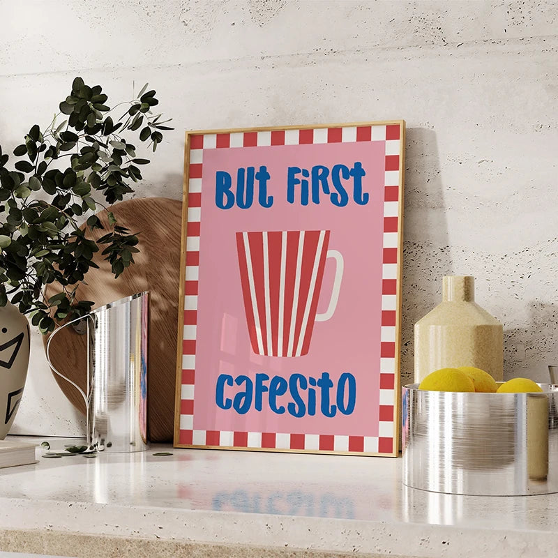 Decorative sign with 'But first, cafesito' text on a pink background, framed in red and white stripes, placed on a surface with decor items.