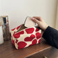 Red and beige patterned tissue box on a wooden surface with a hand reaching for tissues.